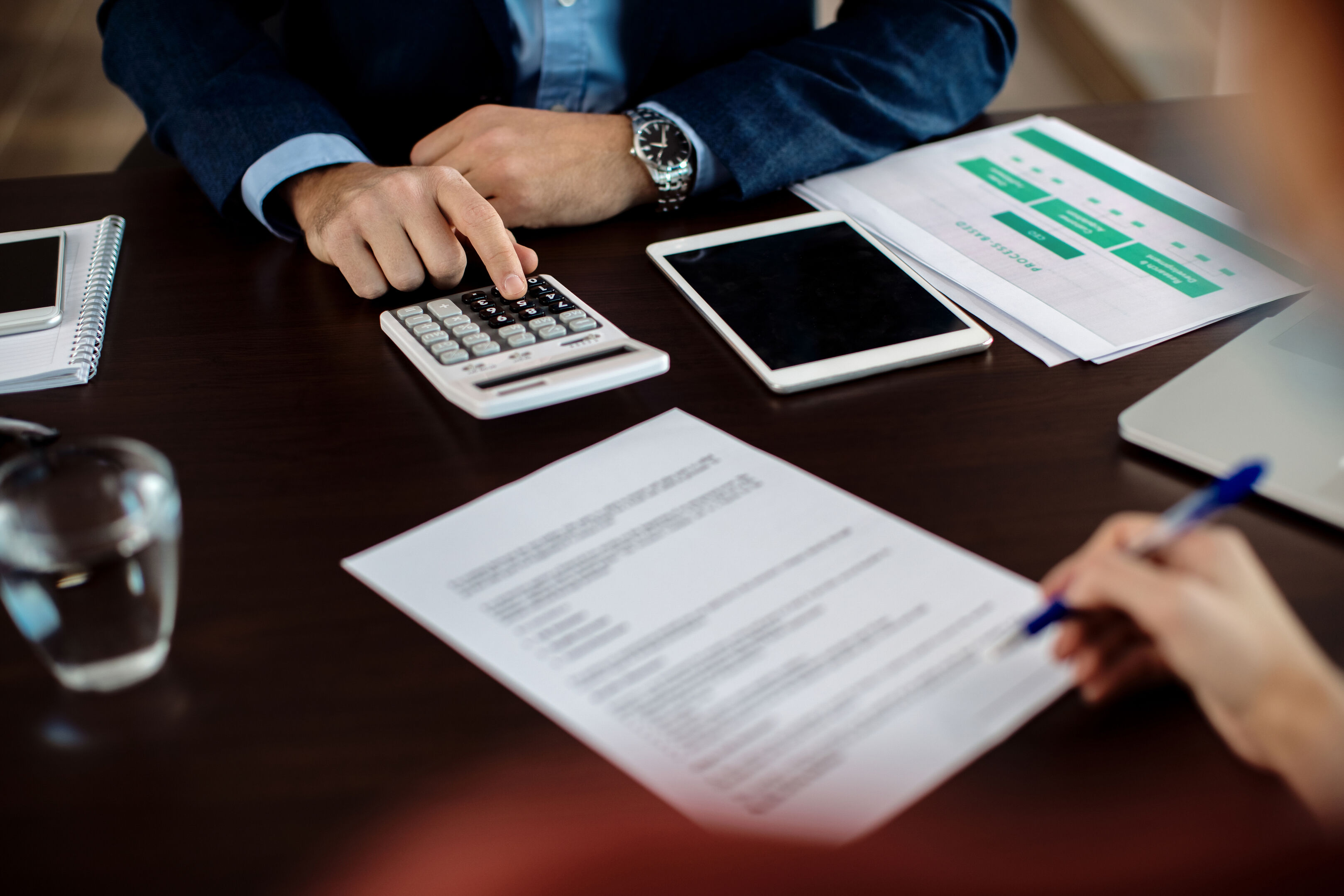 closeup-real-estate-agent-using-calculator-while-his-client-is-signing-contract_2_optimized_2048.0